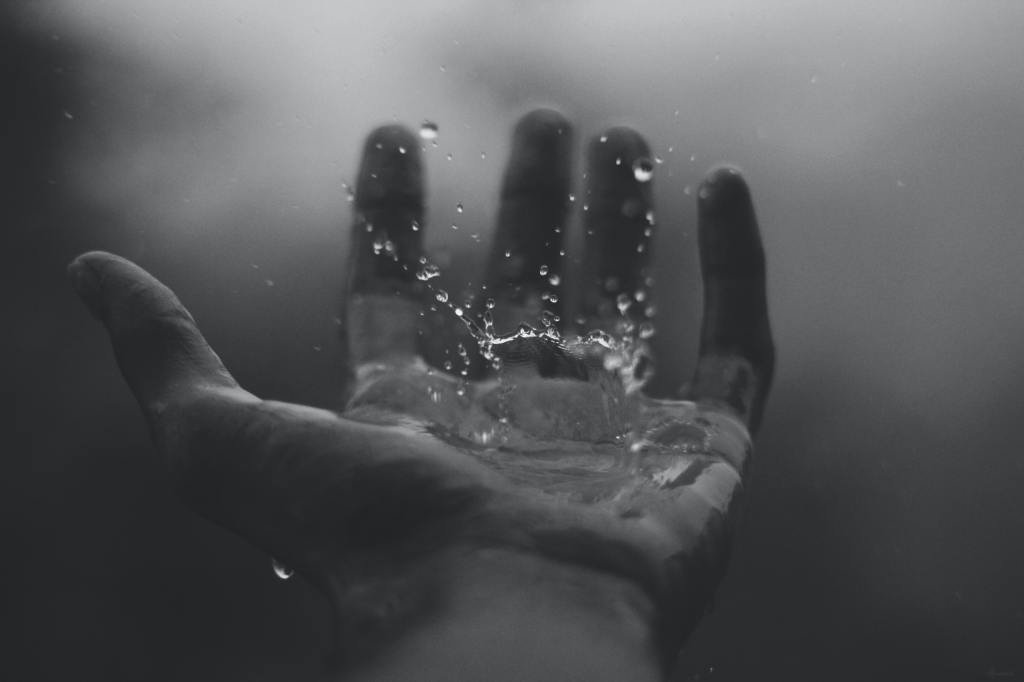 Time lapse greyscale photo of water hitting left palm