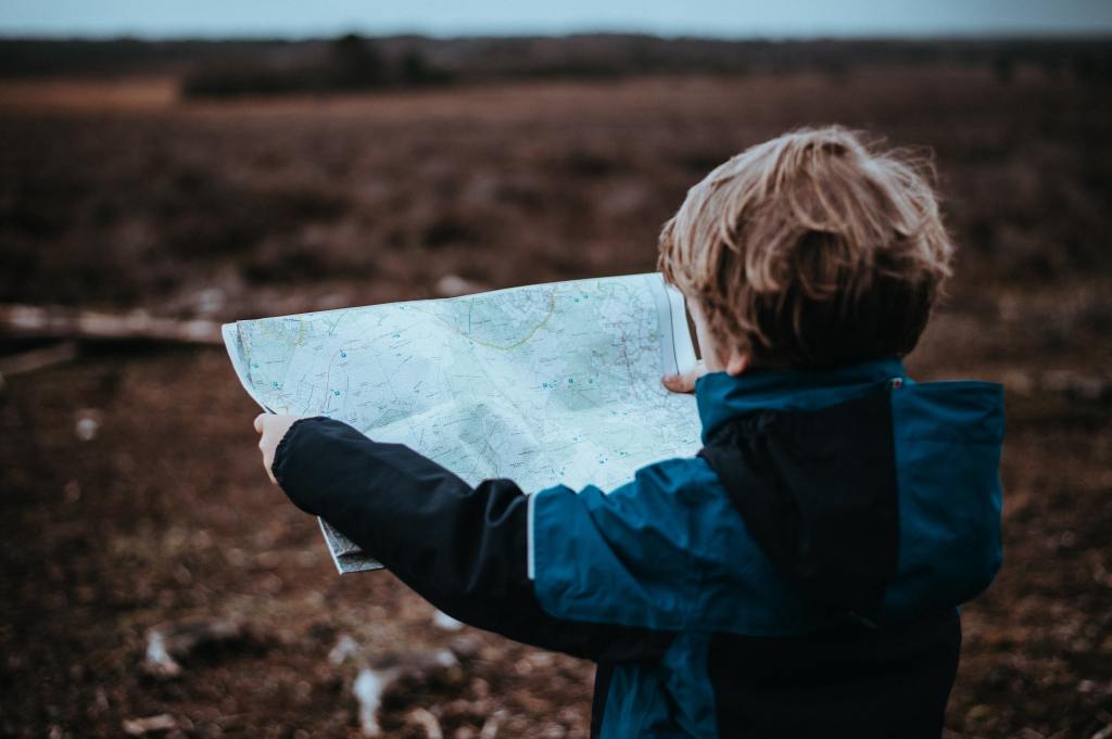 Child in a brown field looking at a map