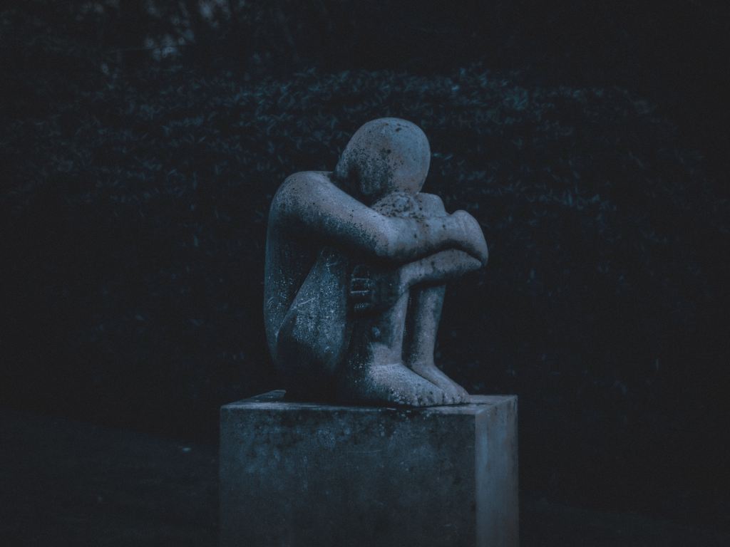 Statue of a person hugging their knees