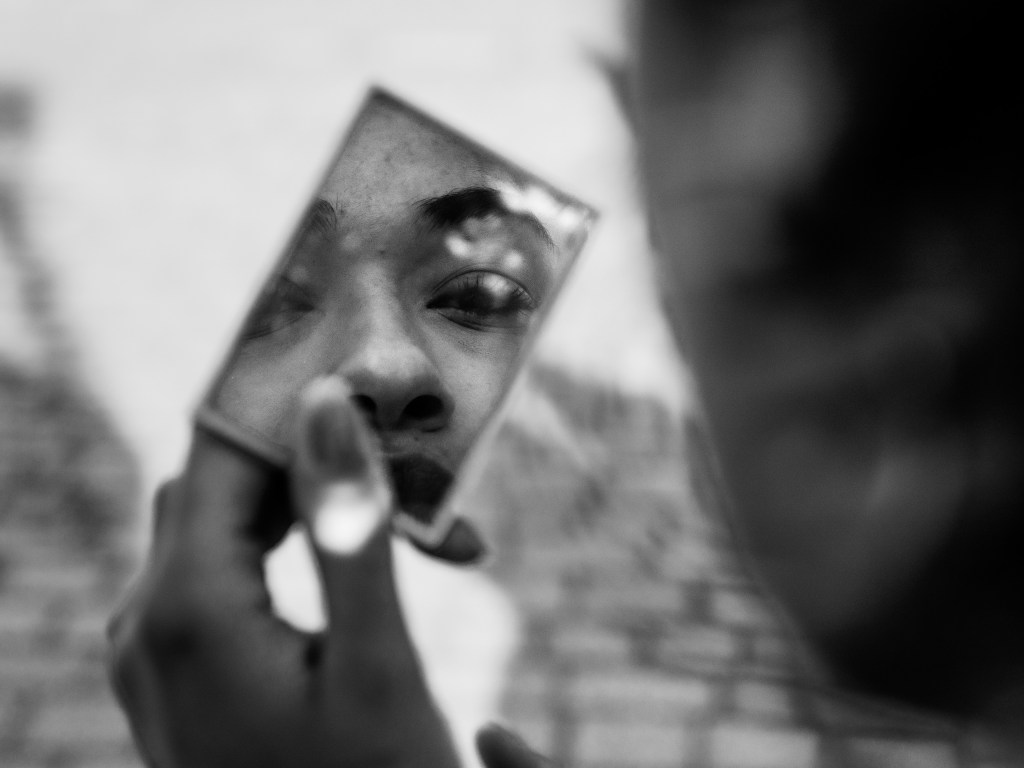 greyscale photo of a person holding a small mirror